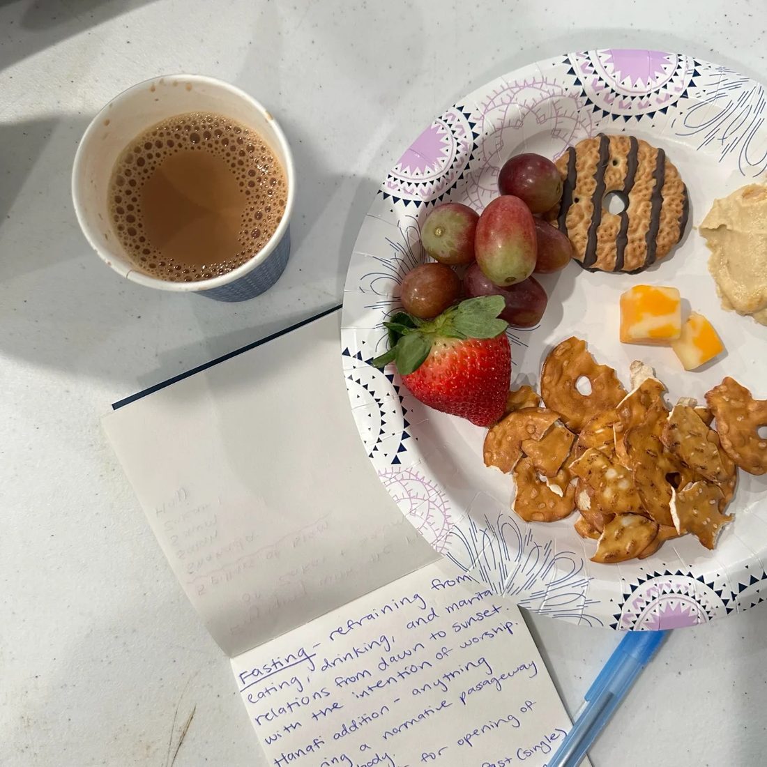 Chai and a plate of food beside handwritten notes.