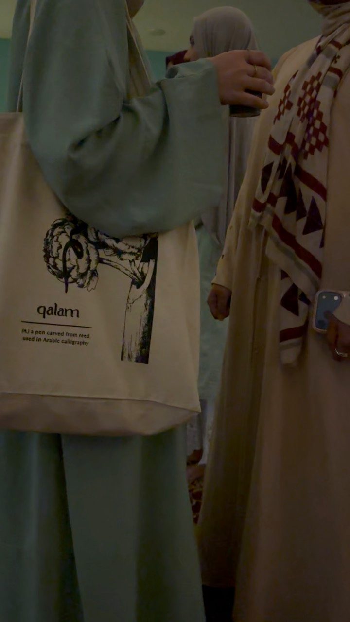 Two attendees talking, one carrying a tote bag.